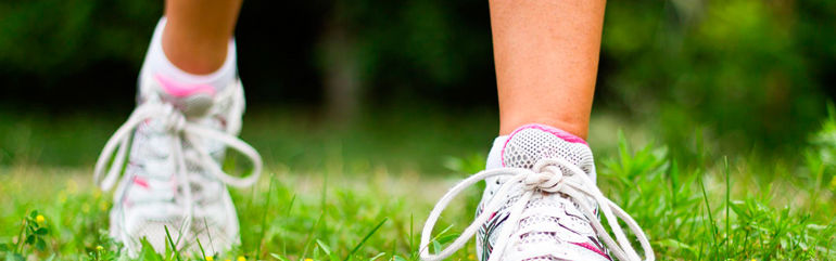 Føtter med joggesko i gras.