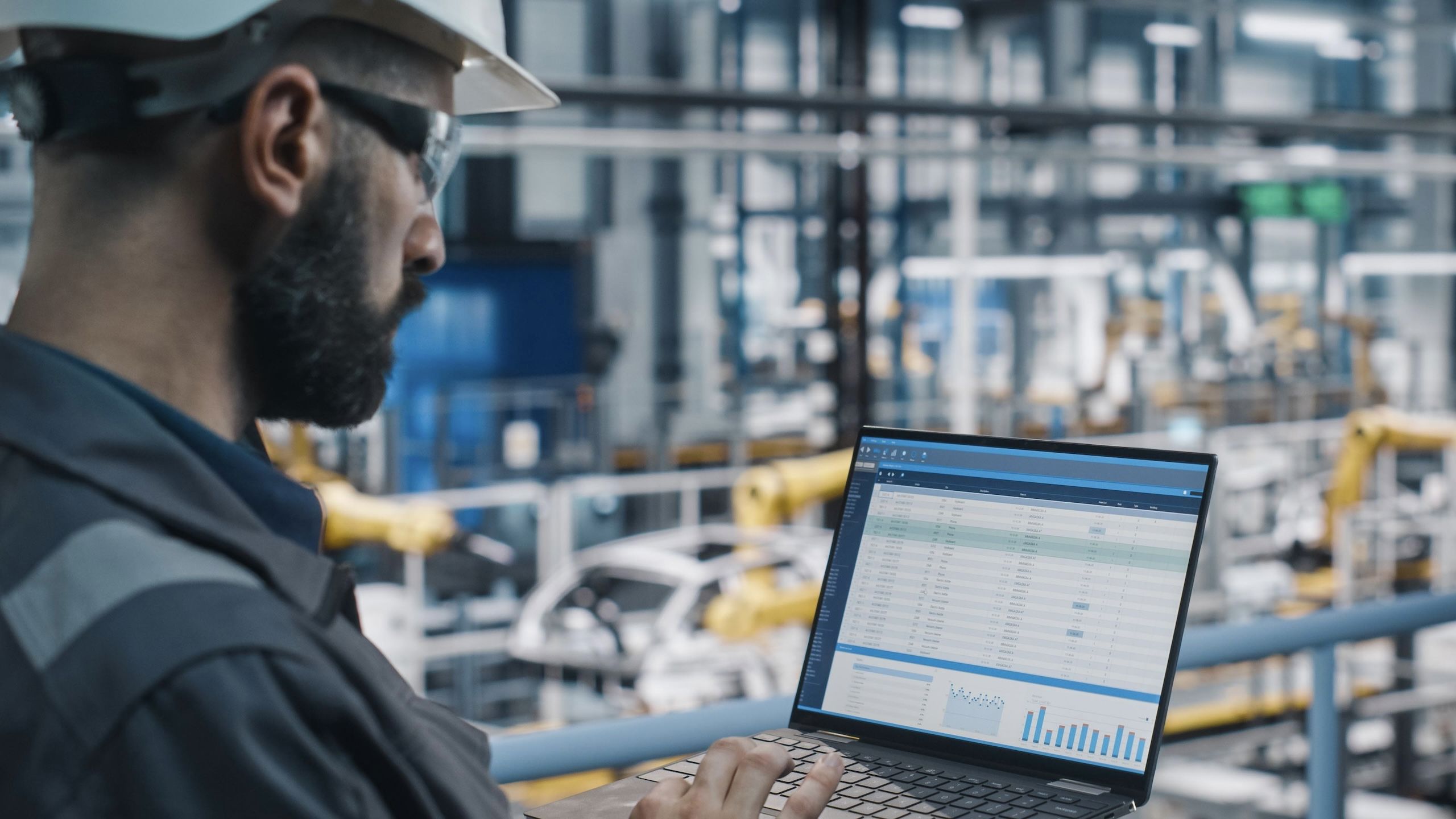 Mann med hjelm og vernebriller trykker på en pc.
