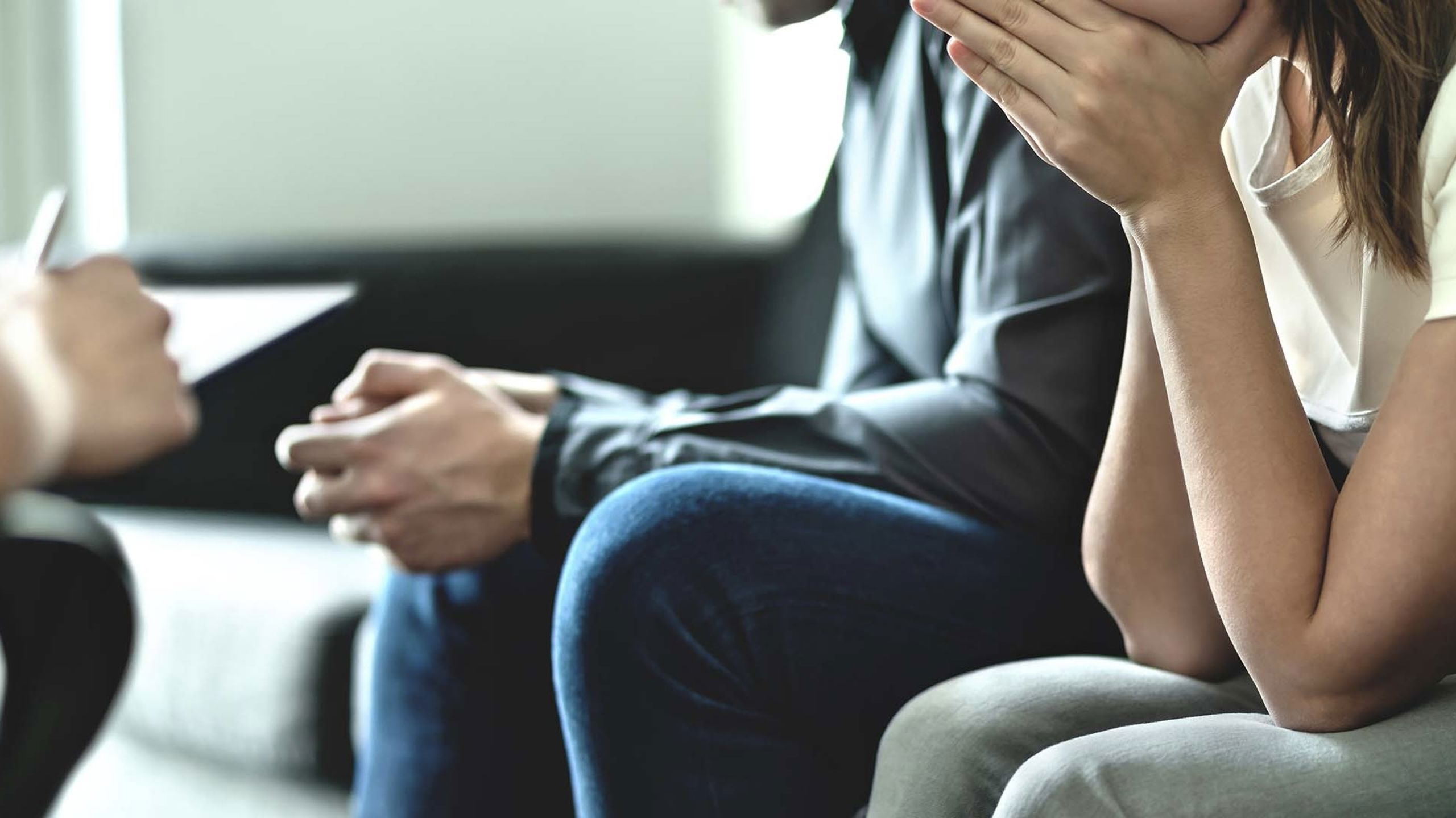 Two people in a couch. You can only see their hans but no face.