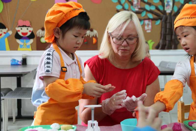 Centre leader Elin Eriksen Ødegaard and two children playing with plasticine.