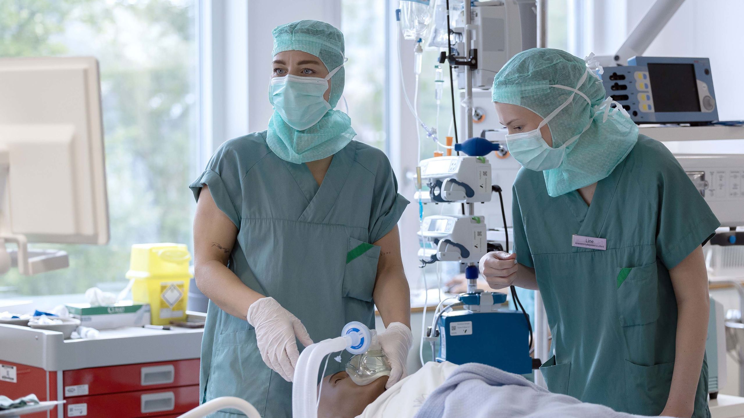 To sykepleiere står over pasient med en maske.