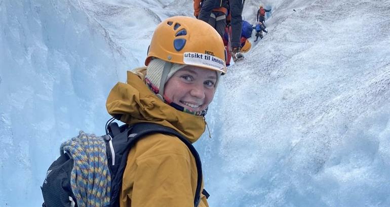 Bilete av kvinneleg geologistudentmed hjelm og klatreutstyr som er på ekskursjon på isbre. 