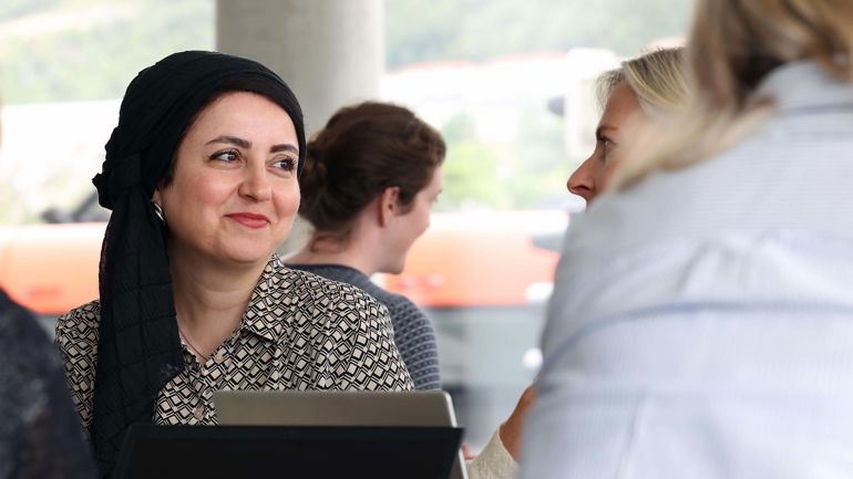 Kvinne med hodeplagg smiler.