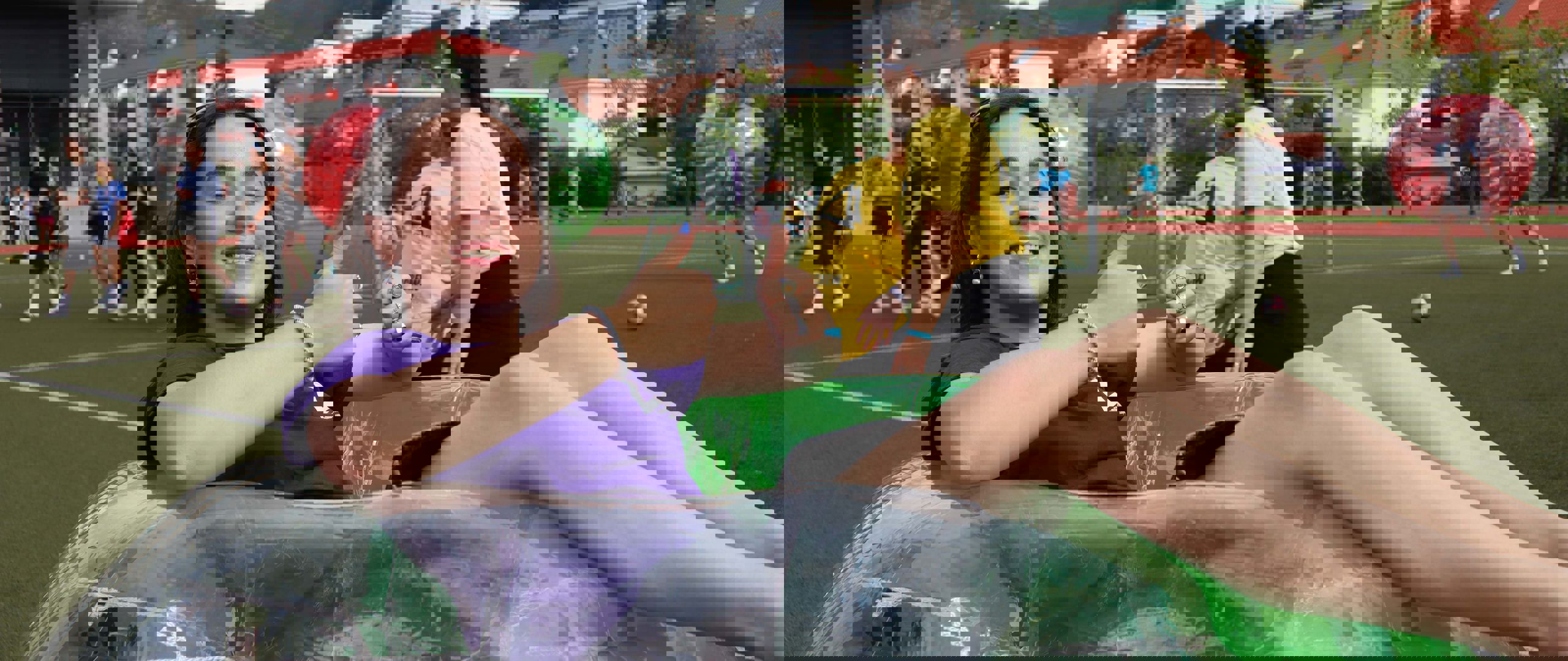 Ein student ligg i ein plastball, smilande og med tomlane opp. Rundt studenten er andre studentar i gang med ulike sportslege aktivitetar i fadderveka.