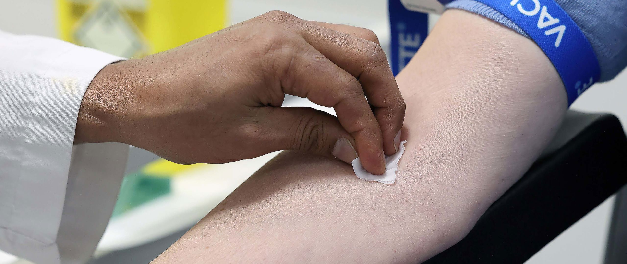 Bilde av hånd som holder over bomullsdott på en annen arm.