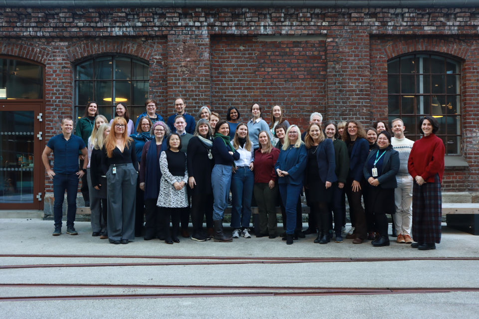 En gruppe mennesker fra BARNkunne og Kunnskapsdepartementet, som står foran en murvegg.