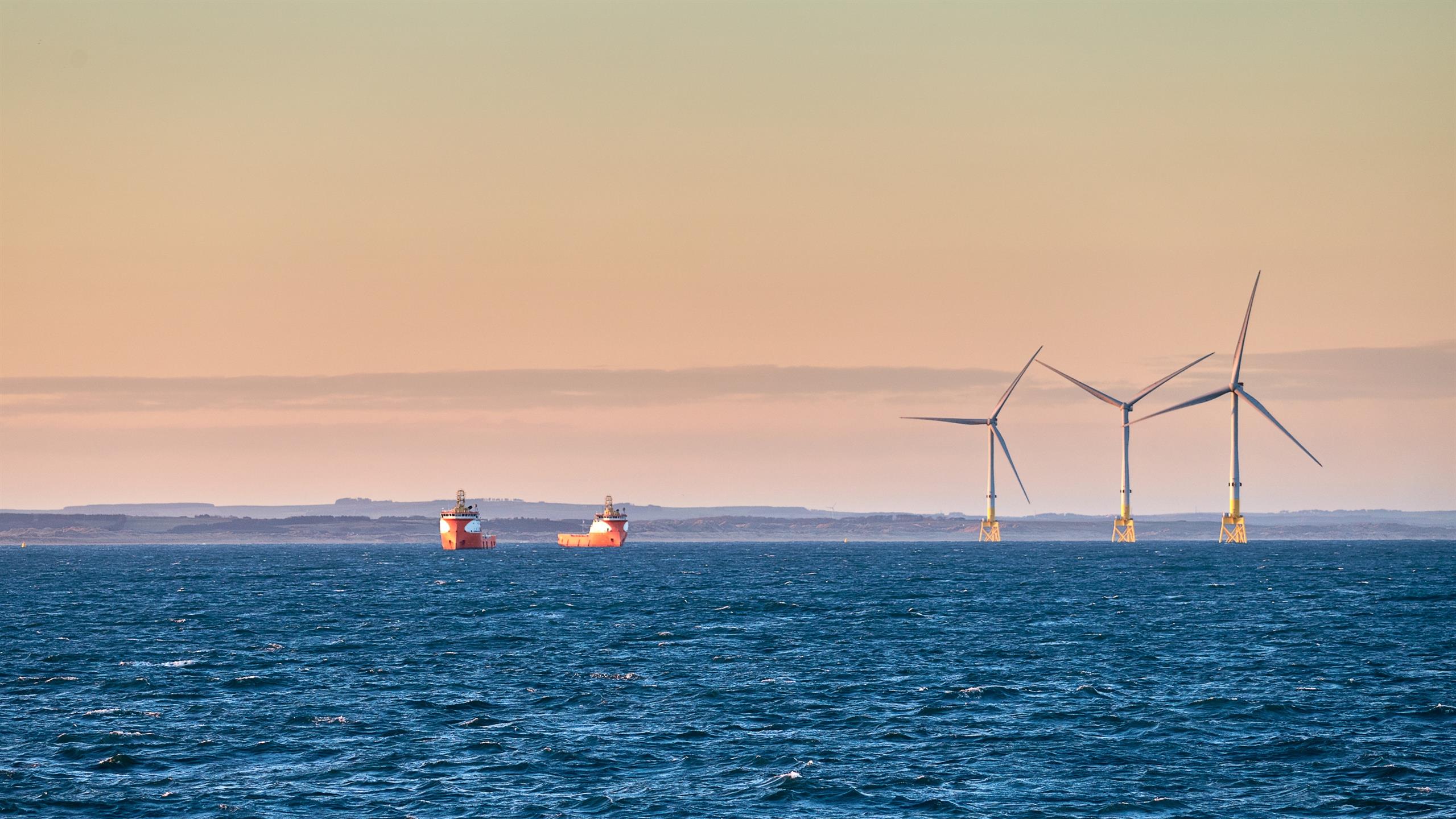 To skip på havet ved siden av vindmøller. 