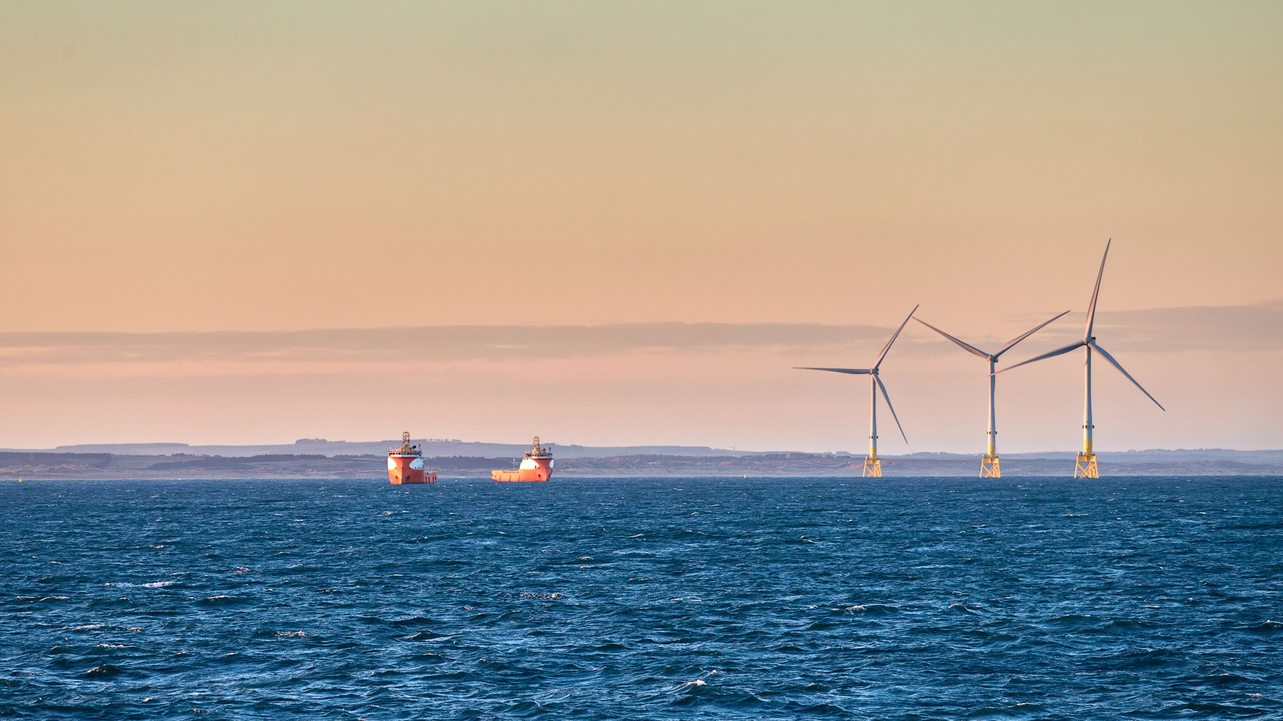 To skip på havet ved siden av vindmøller.