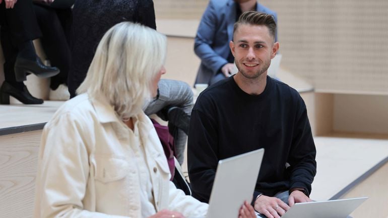 To personer sitter med bærbar pc på fanget. Mann ser inn i kameraet og smiler.