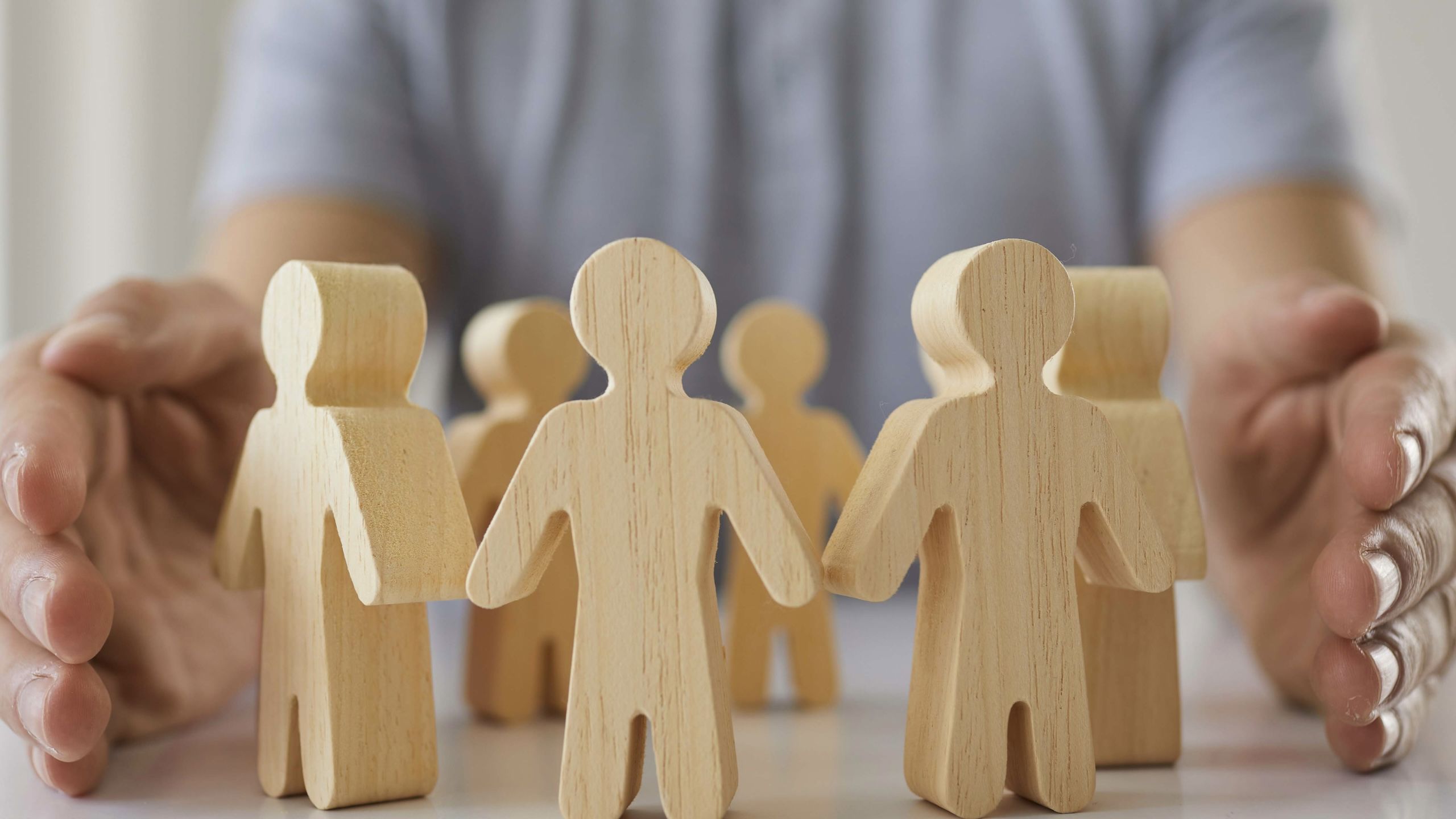 To hender holder rundt trefigurer som er formet som mennesker.