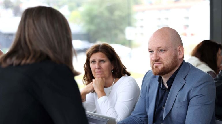 En dame og en mann ser på en dame som sitter med ryggen til.