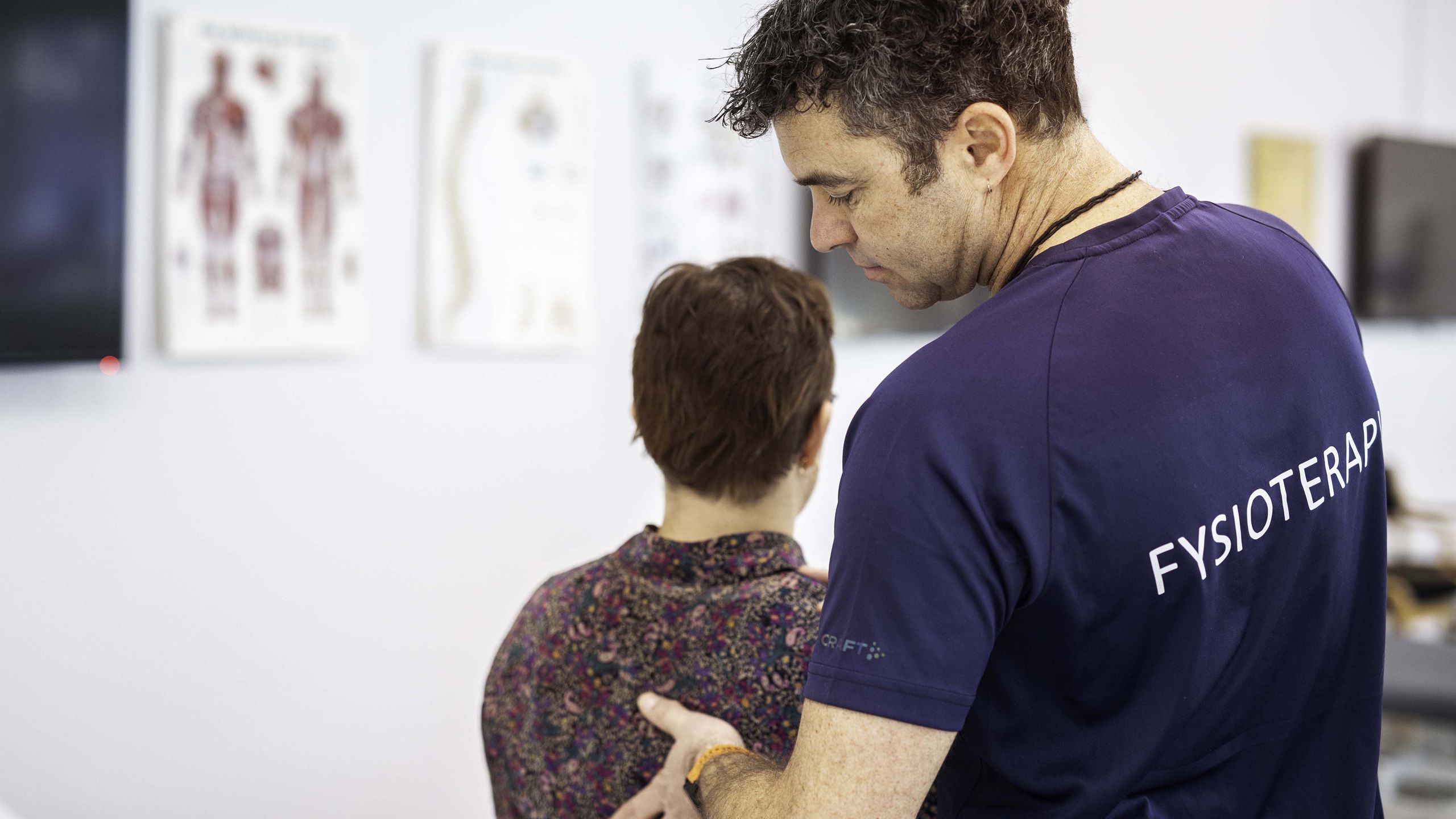 Ein fysioterapeut som kjenner på ryggen til ein pasient.