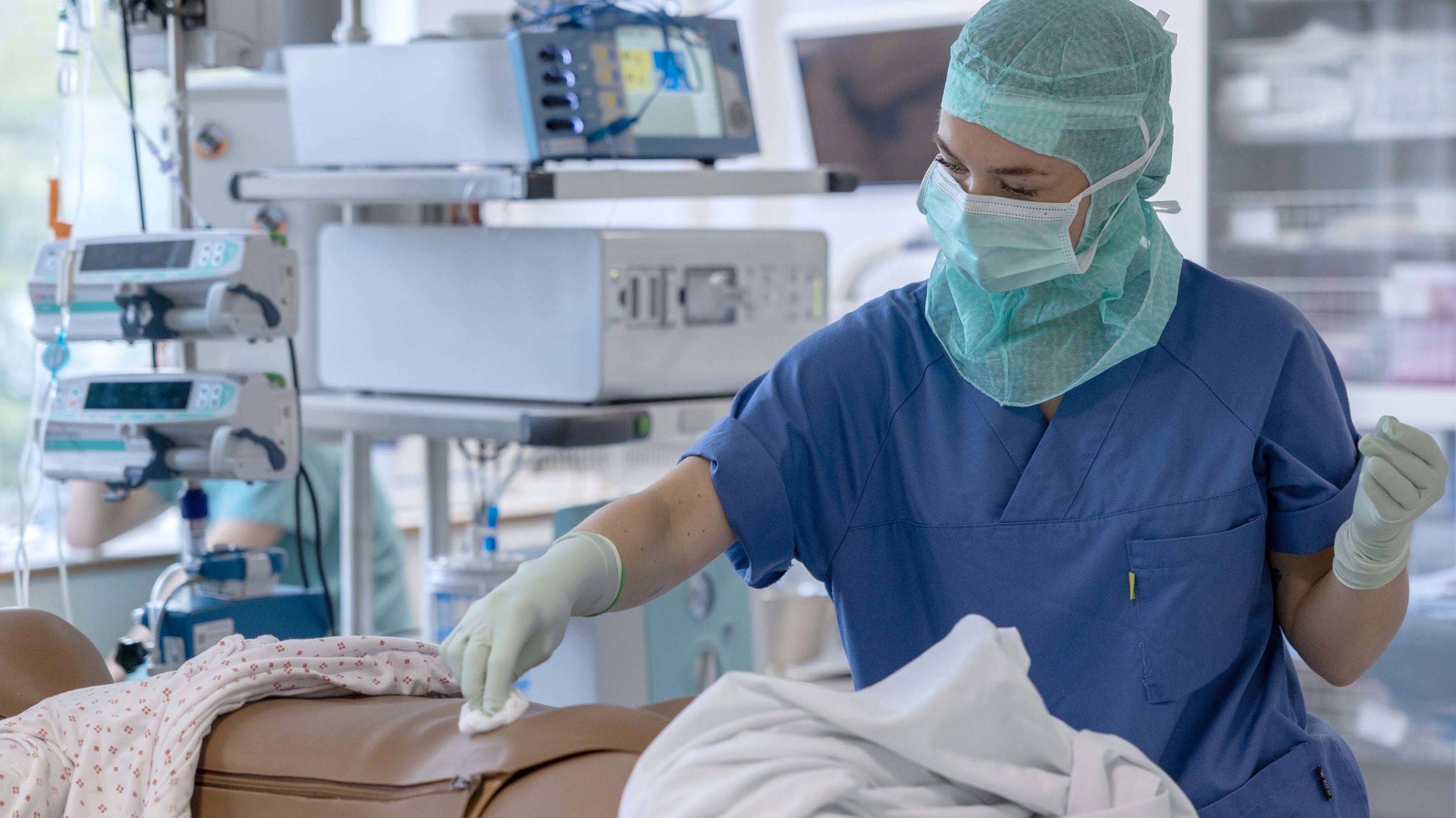 Sykepleier i uniform tørker av magen på en dukke med bomull.