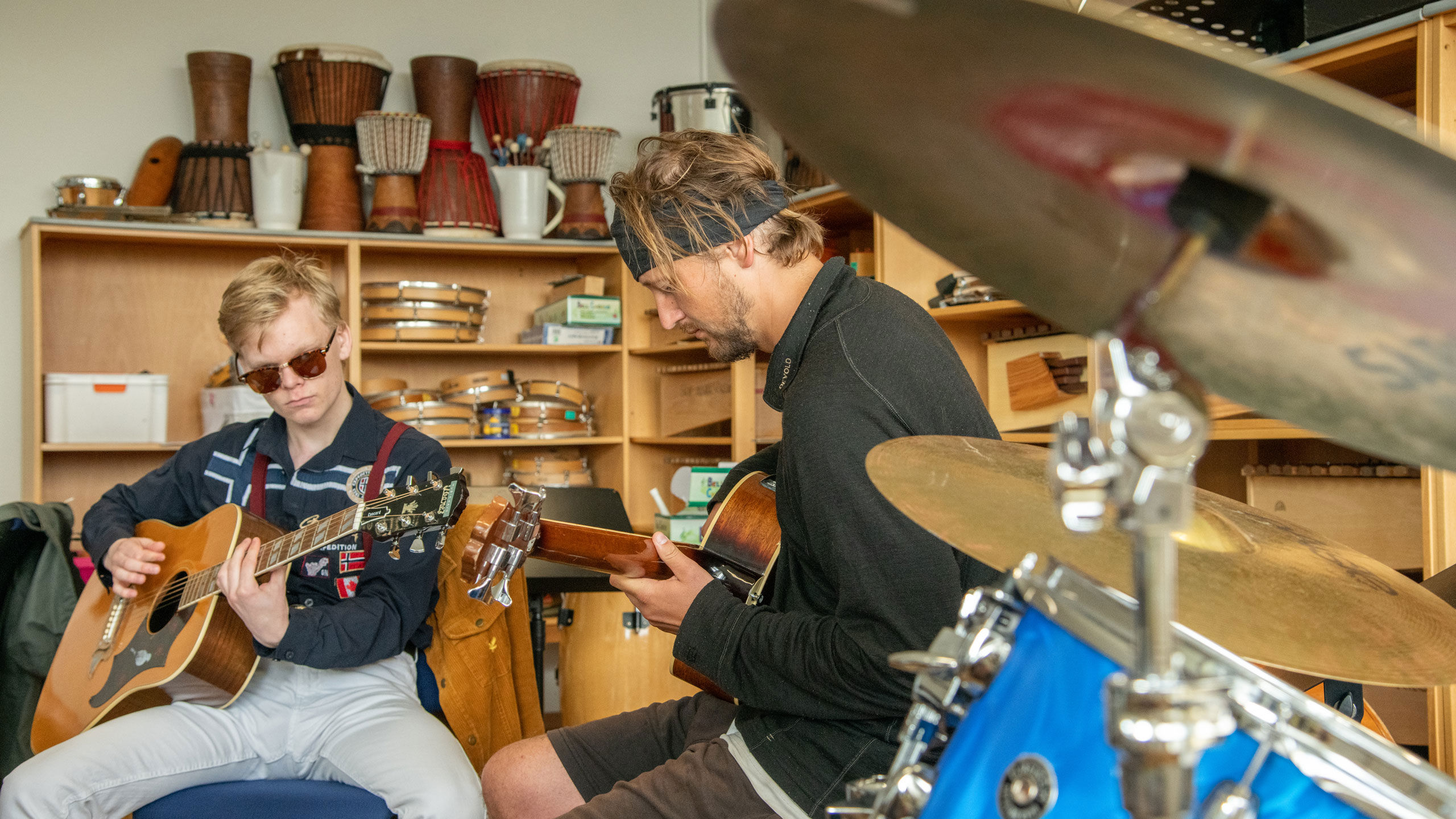 To person som sitter rundt andre instrumenter og spiller gitar