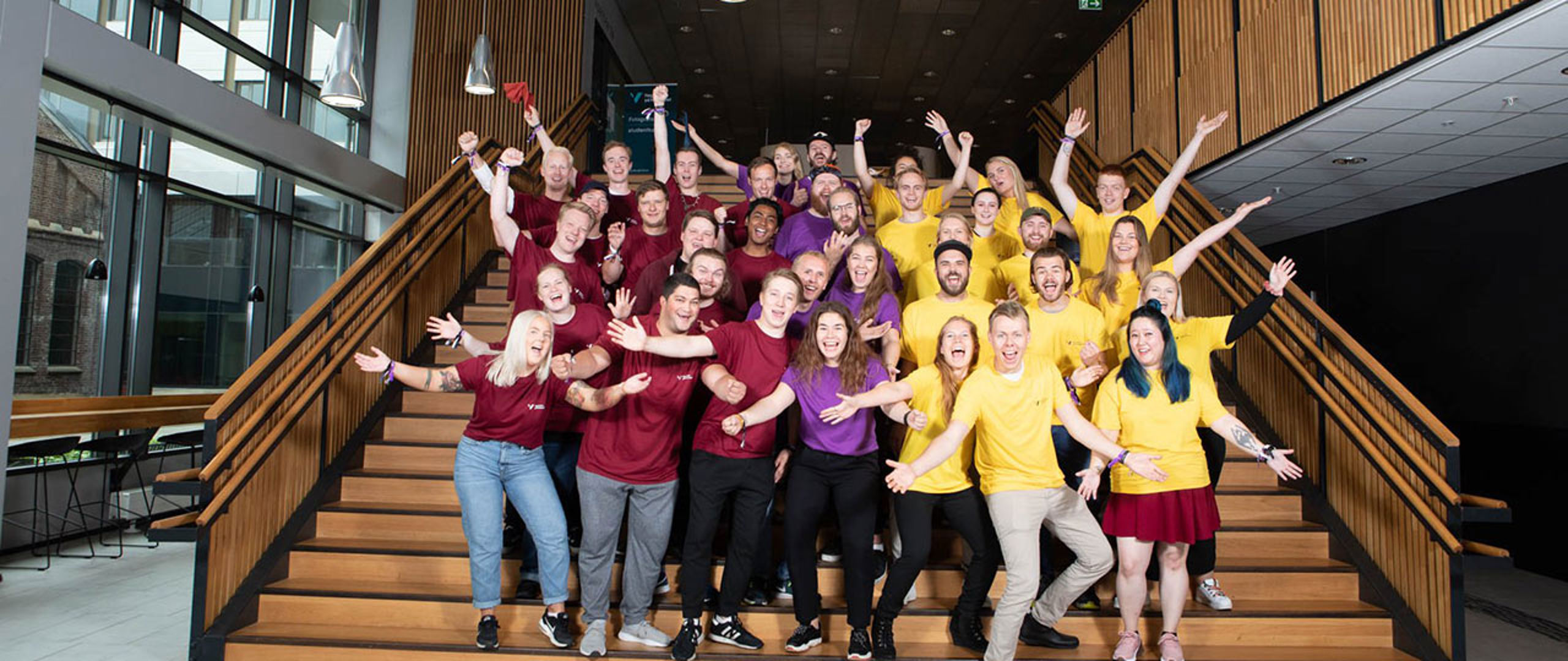 Blid gjeng med fadrar i trapp inne på campus Bergen.