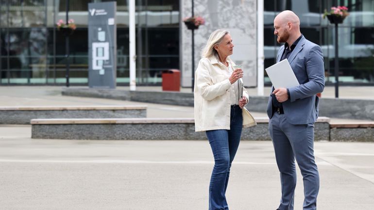 En mann og en dame står utenfor HVL campus Bergen.