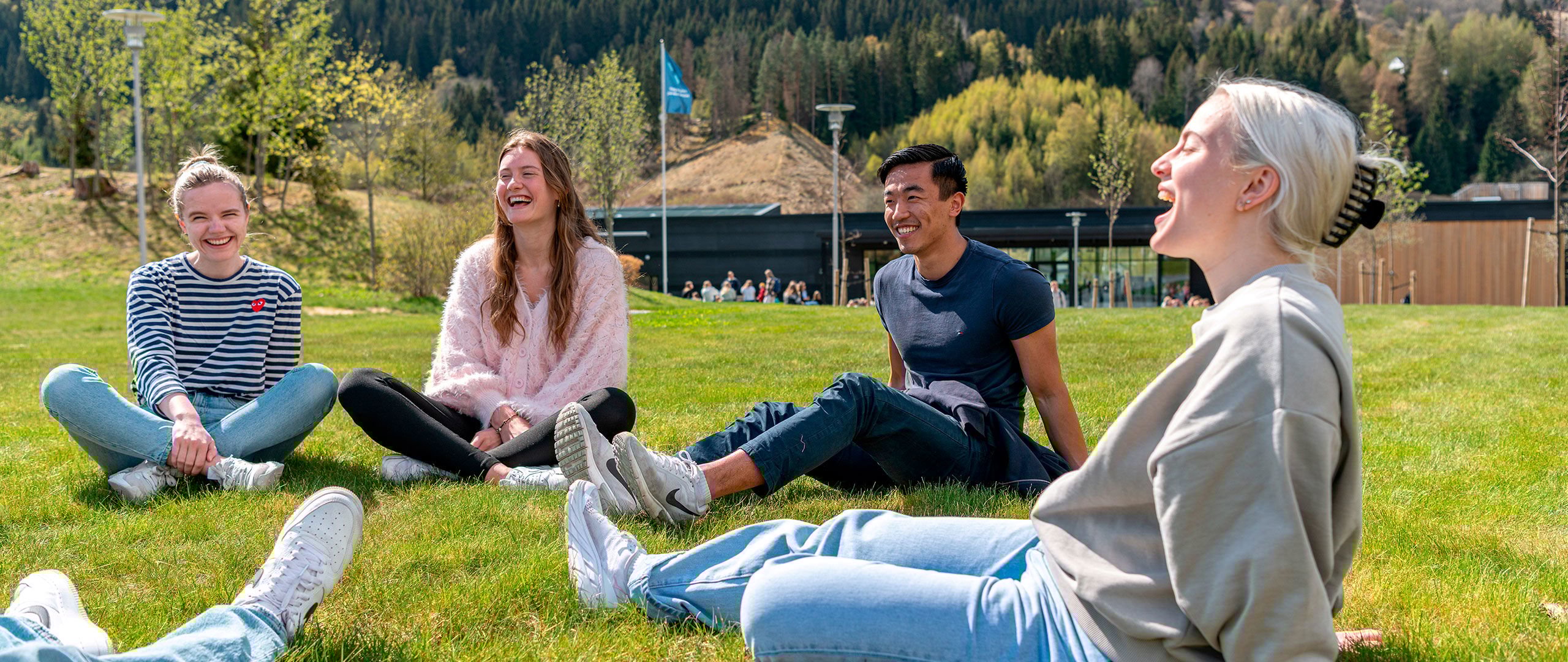 Blide studentar sittande ute på graset.
