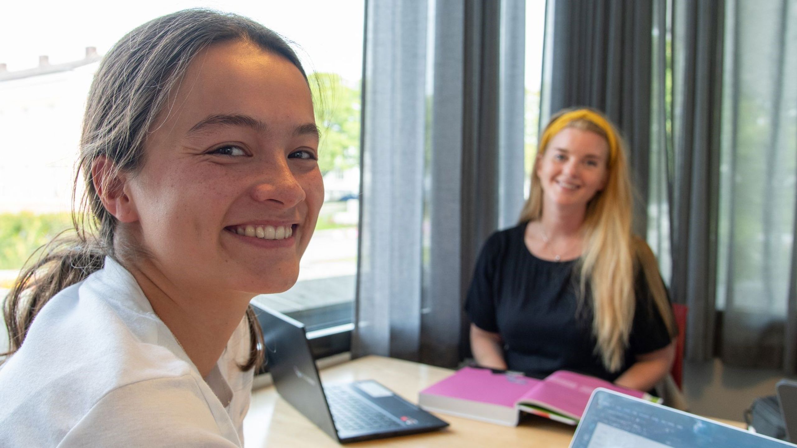 Kvinnelige studenter med pc og pensumbok